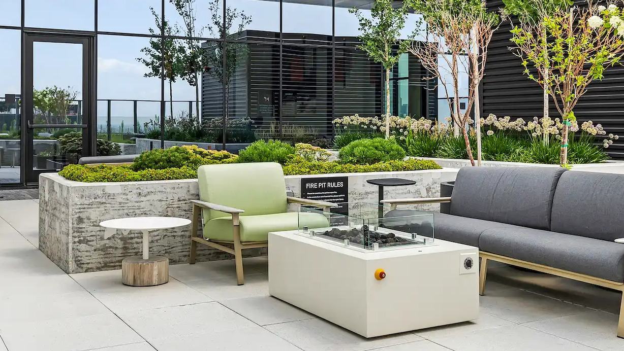 Beautiful outdoor lounge area at The Elizabeth Chicago, featuring comfortable seating, a modern fire pit, and landscaped greenery
