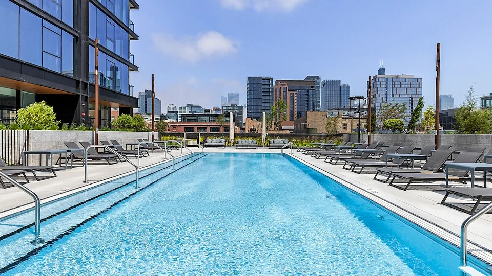 Expansive outdoor swimming pool deck at The Elizabeth Chicago, featuring lounge chairs and panoramic city skyline views