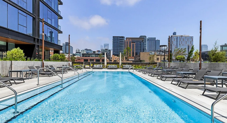 Expansive outdoor swimming pool deck at The Elizabeth Chicago, featuring lounge chairs and panoramic city skyline views