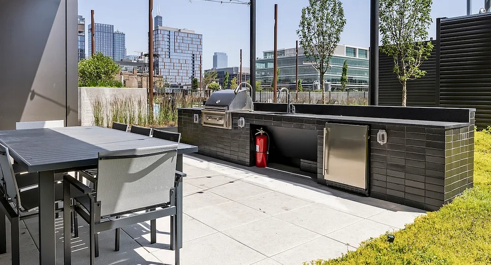 Expansive rooftop grilling area at The Elizabeth Chicago, featuring modern BBQ stations and outdoor dining tables