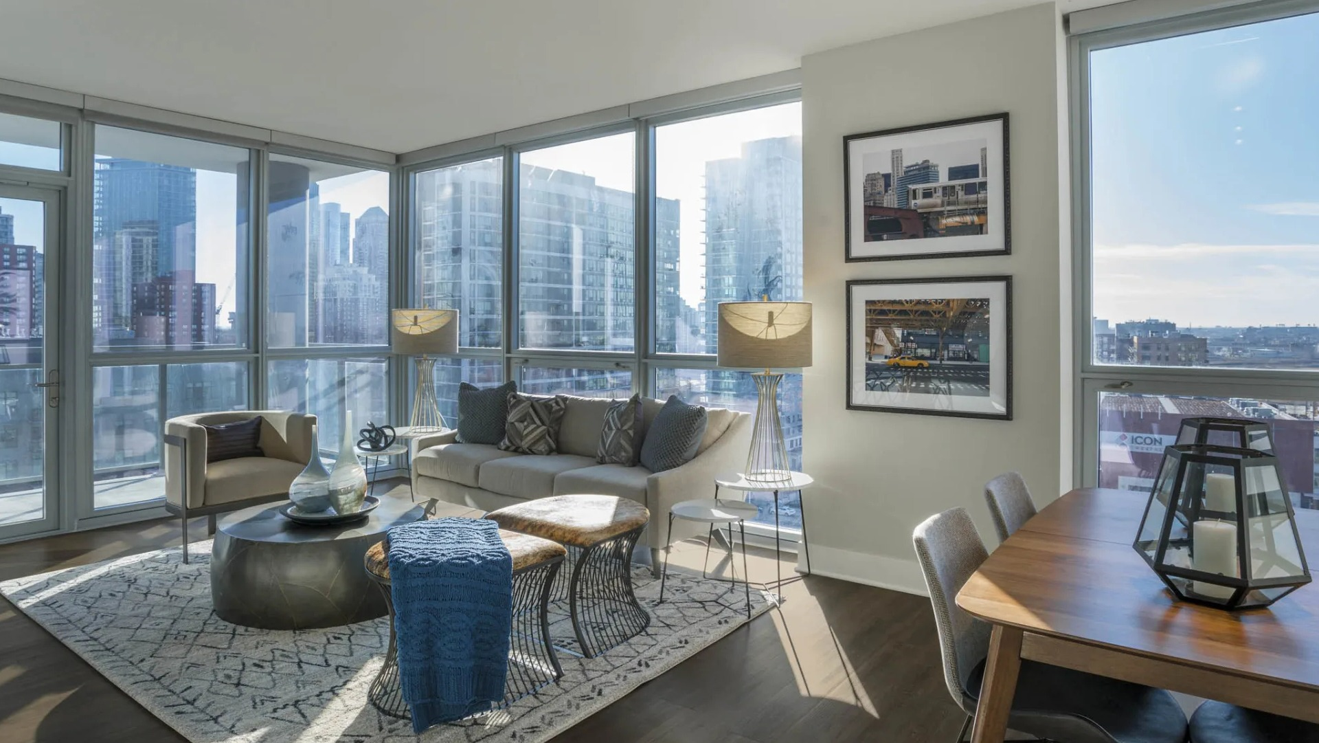 Modern apartment living space with floor-to-ceiling windows, comfortable sofa, and dining area, offering bright city views at The Elle in Chicago