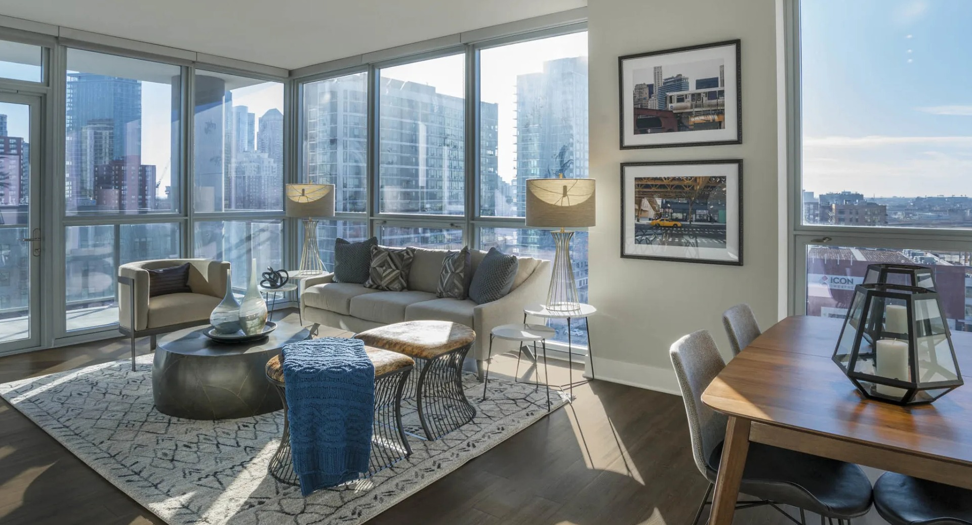 Modern apartment living space with floor-to-ceiling windows, comfortable sofa, and dining area, offering bright city views at The Elle in Chicago