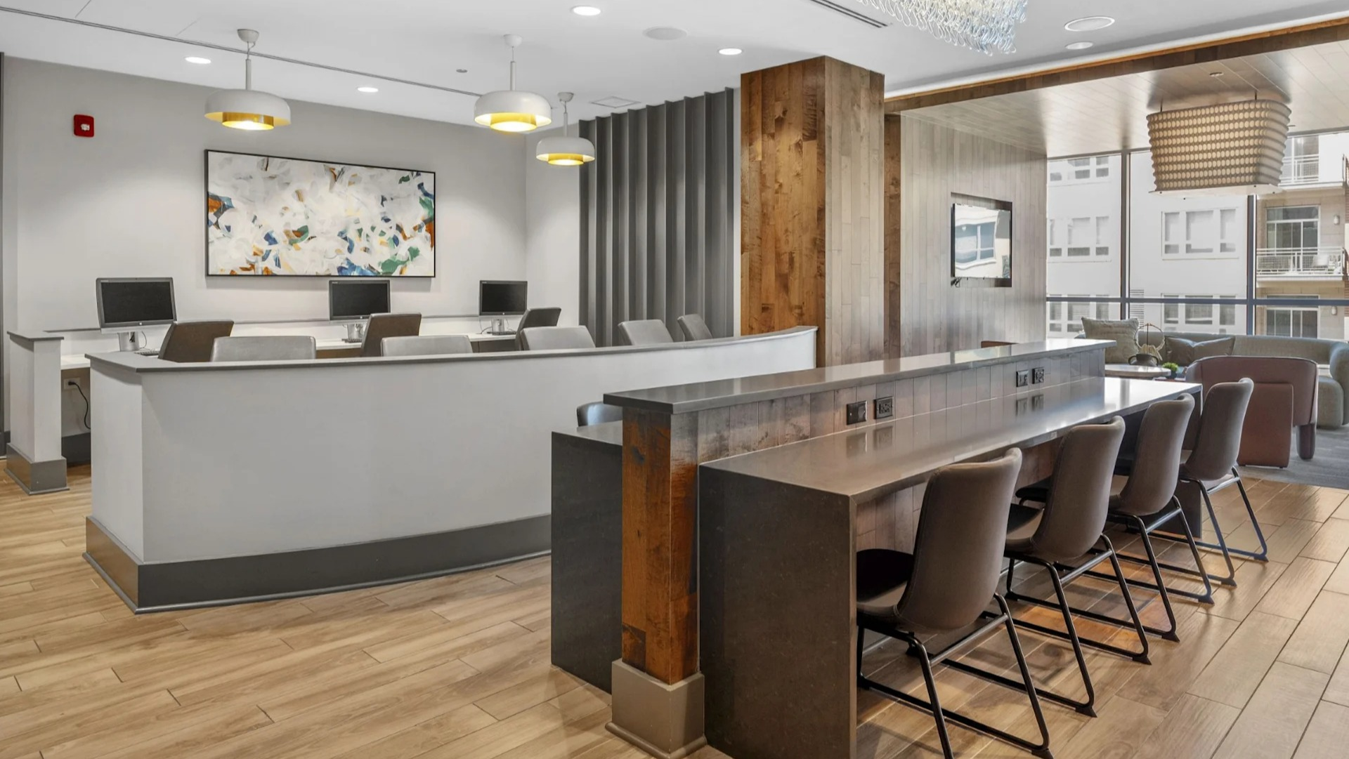 Modern business center and co-working space with individual computer stations and a communal high-top table at The Elle in Chicago