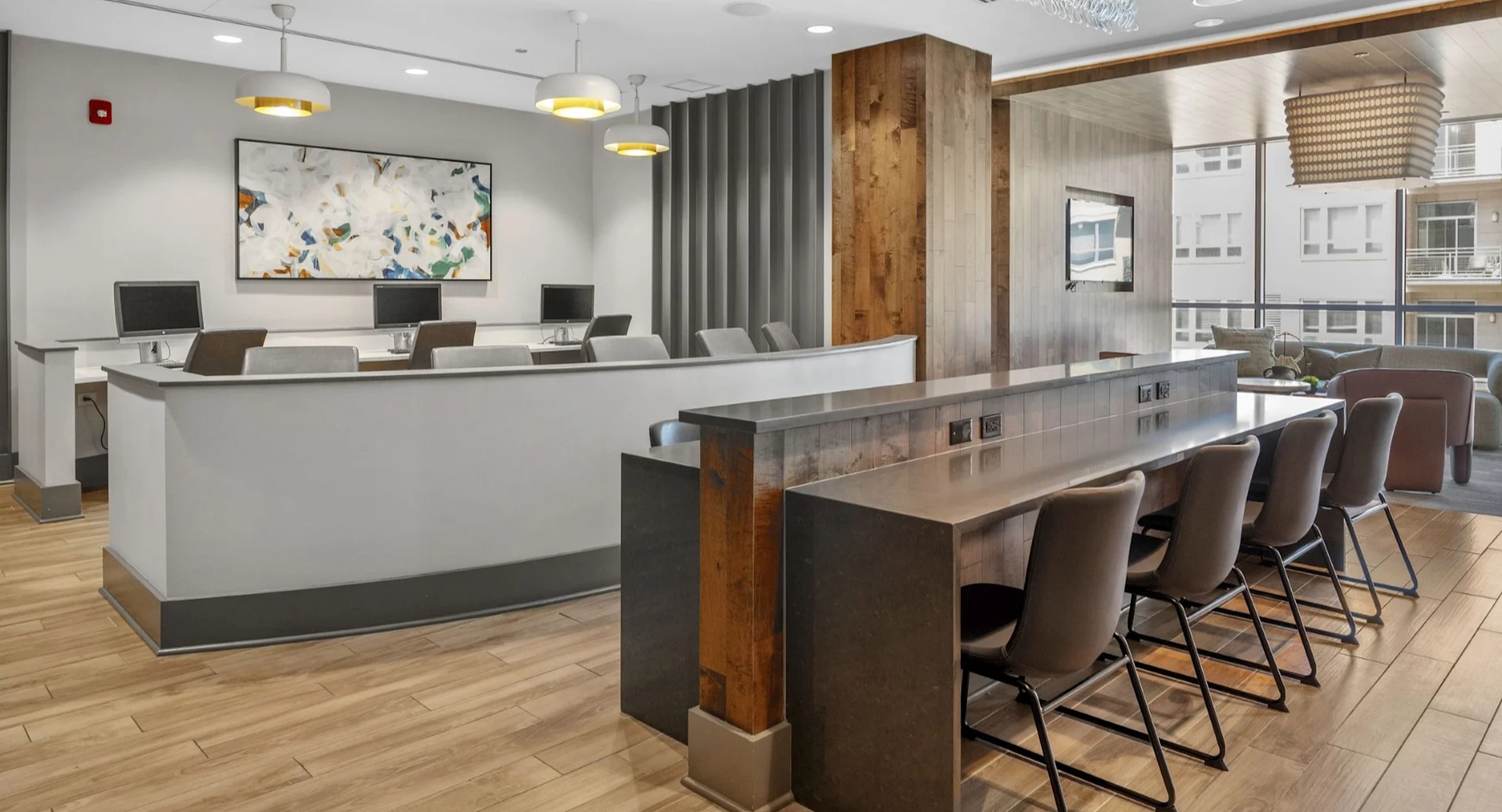 Modern business center and co-working space with individual computer stations and a communal high-top table at The Elle in Chicago