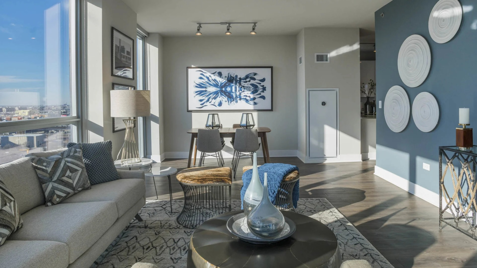 Spacious living and dining area with comfortable seating, a dining table, and large windows providing cityscape views at The Elle in Chicago