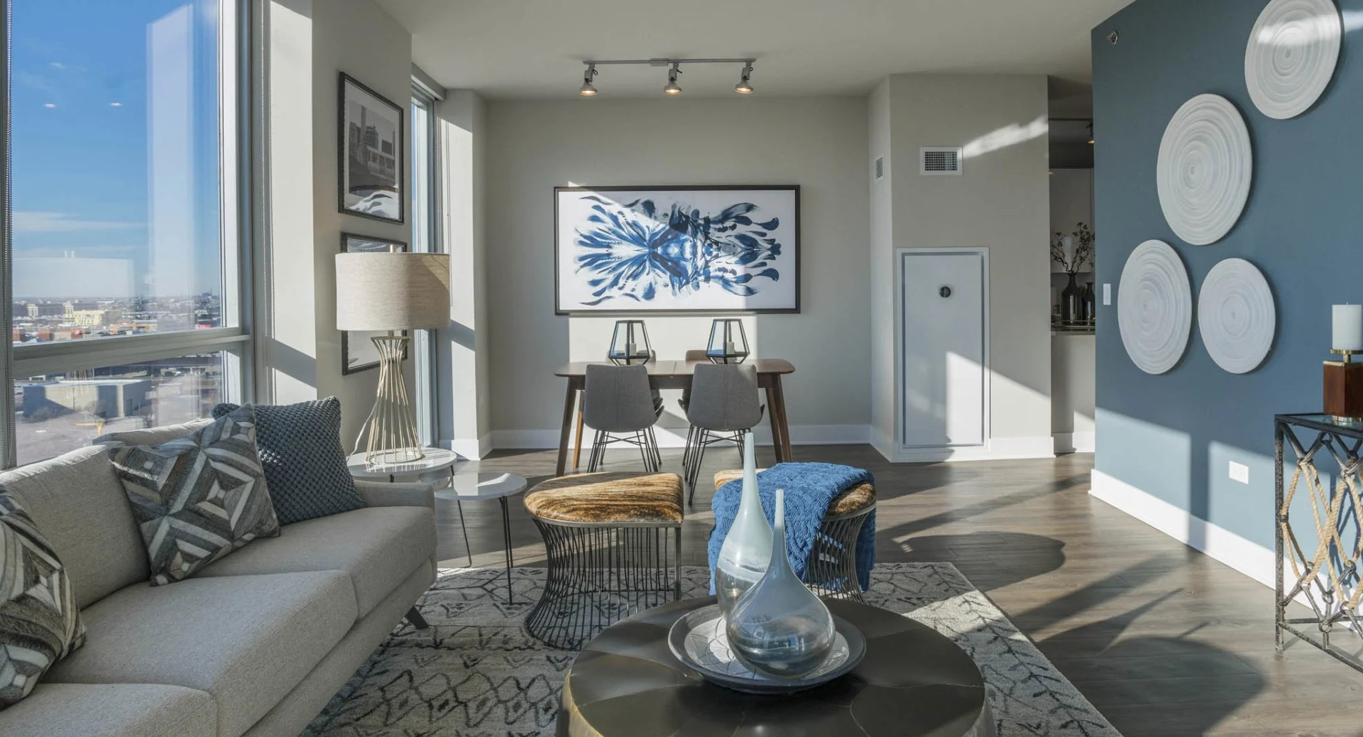 Spacious living and dining area with comfortable seating, a dining table, and large windows providing cityscape views at The Elle in Chicago