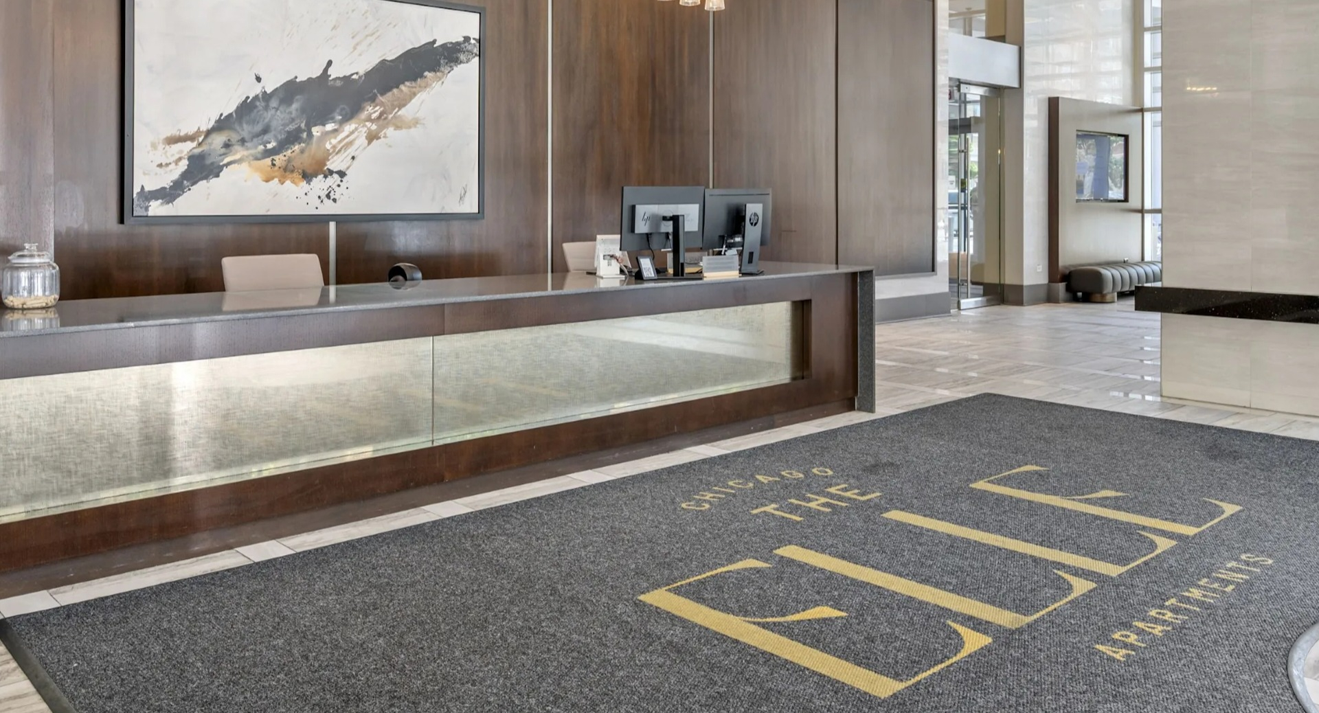 Elegant main lobby and reception area with a stylish desk, modern lighting, and a welcome mat for The Elle Apartments in Chicago
