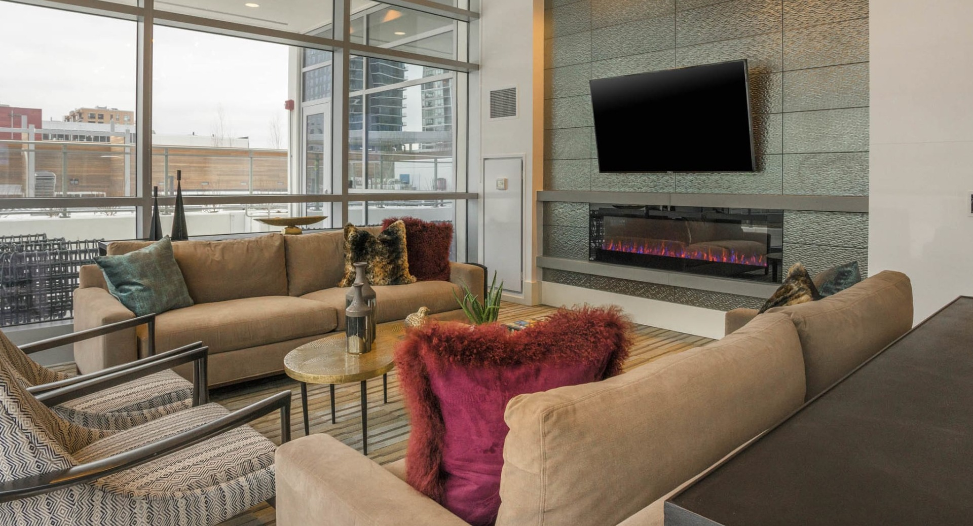 Luxurious resident media lounge with comfortable sofas, a large screen TV, a modern fireplace, and city views at The Elle in Chicago