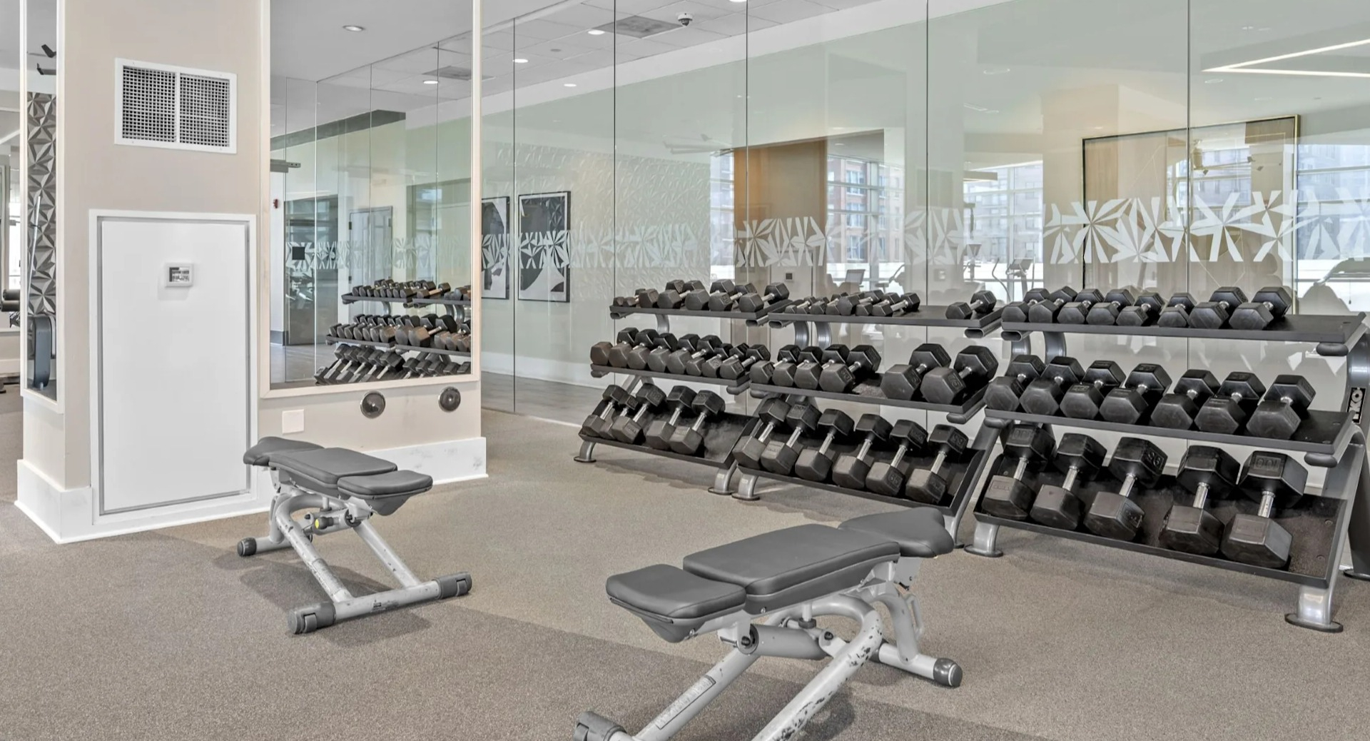 Dedicated strength training gym equipped with various free weights, benches, and machines in a modern, spacious setting at The Elle in Chicago
