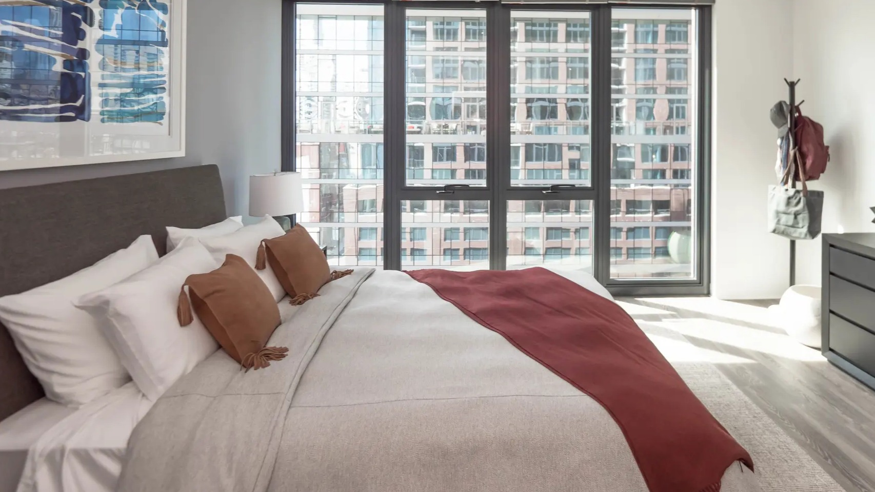 Spacious bedroom with a comfortable bed, large windows offering city views, and modern dark wood furniture at The Gallery on Wells in Chicago