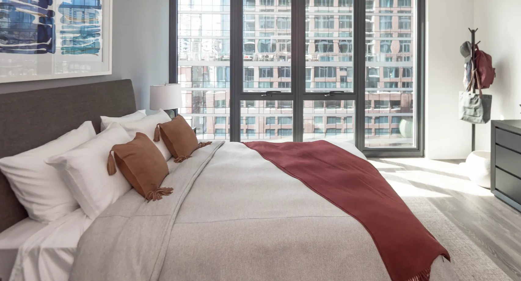 Spacious bedroom with a comfortable bed, large windows offering city views, and modern dark wood furniture at The Gallery on Wells in Chicago