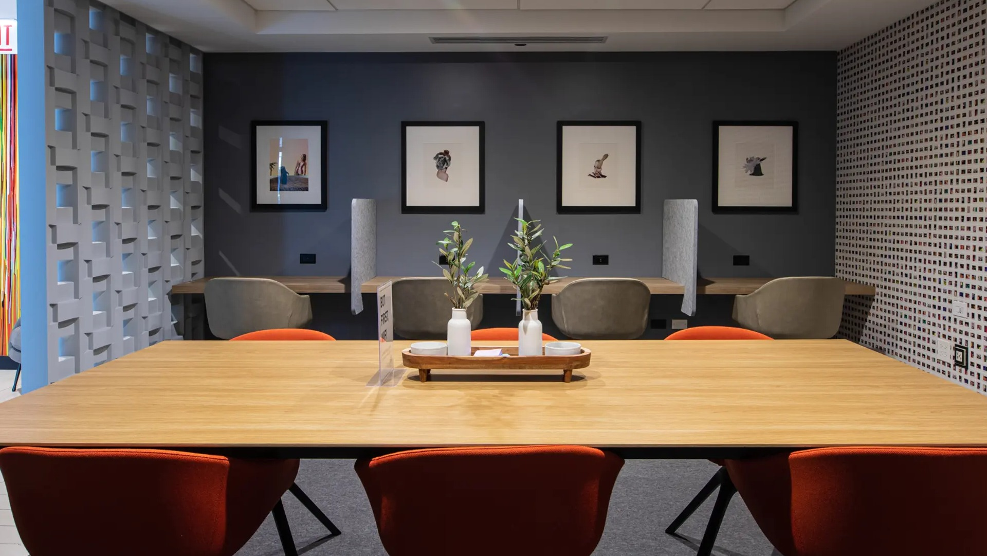 Modern business lounge featuring a large communal table, private work pods, and vibrant artwork at The Gallery on Wells in Chicago