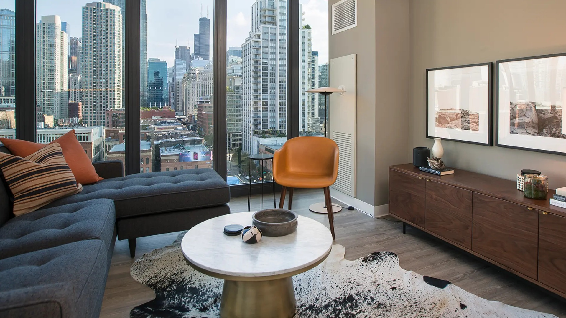 Chic living space with modern furniture, unique rug, and large windows offering panoramic city views at The Gallery on Wells in Chicago