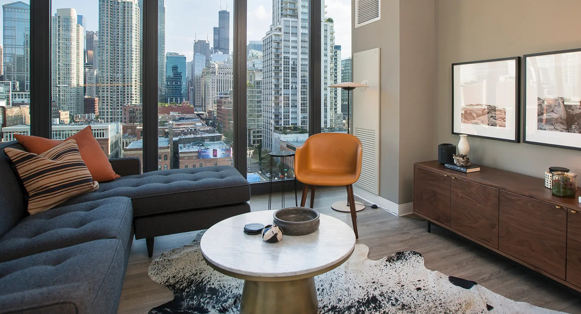 Chic living space with modern furniture, unique rug, and large windows offering panoramic city views at The Gallery on Wells in Chicago