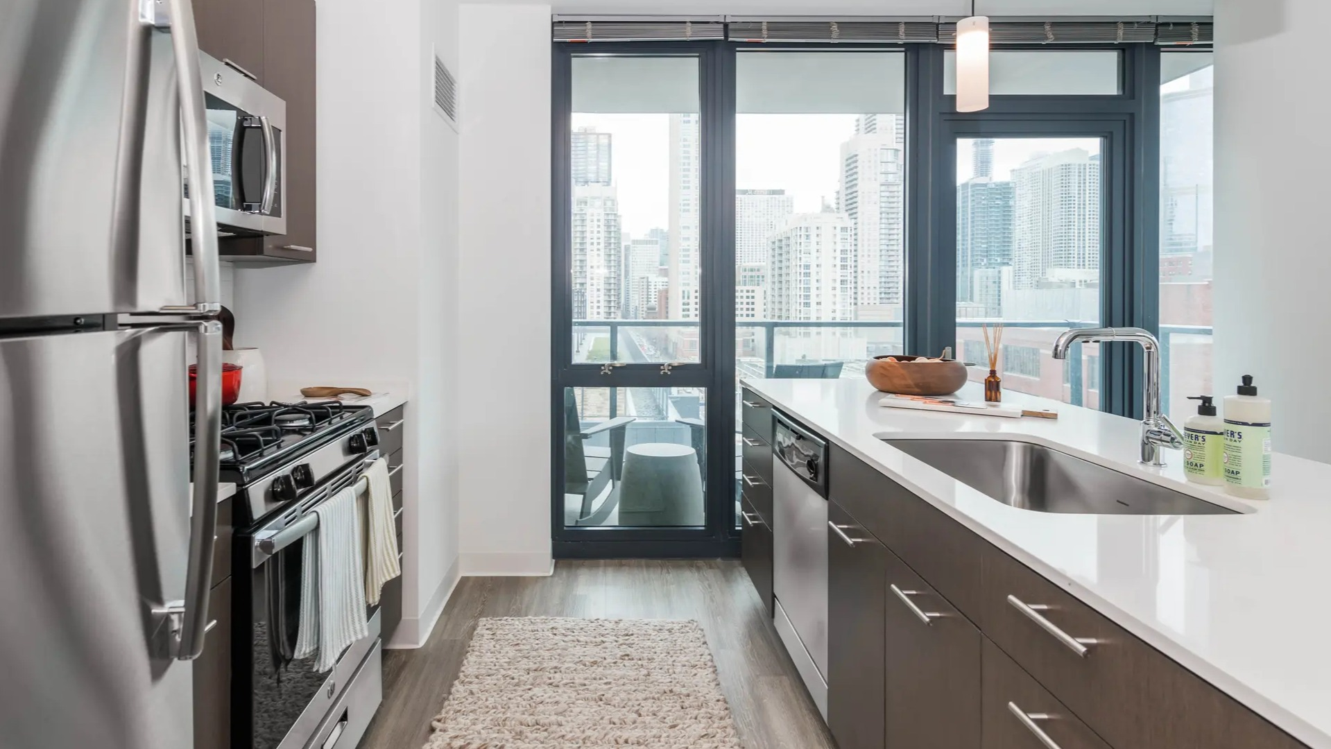 Modern galley kitchen with dark wood cabinets, stainless steel appliances, and a breakfast bar, featuring city views at The Gallery on Wells in Chicago