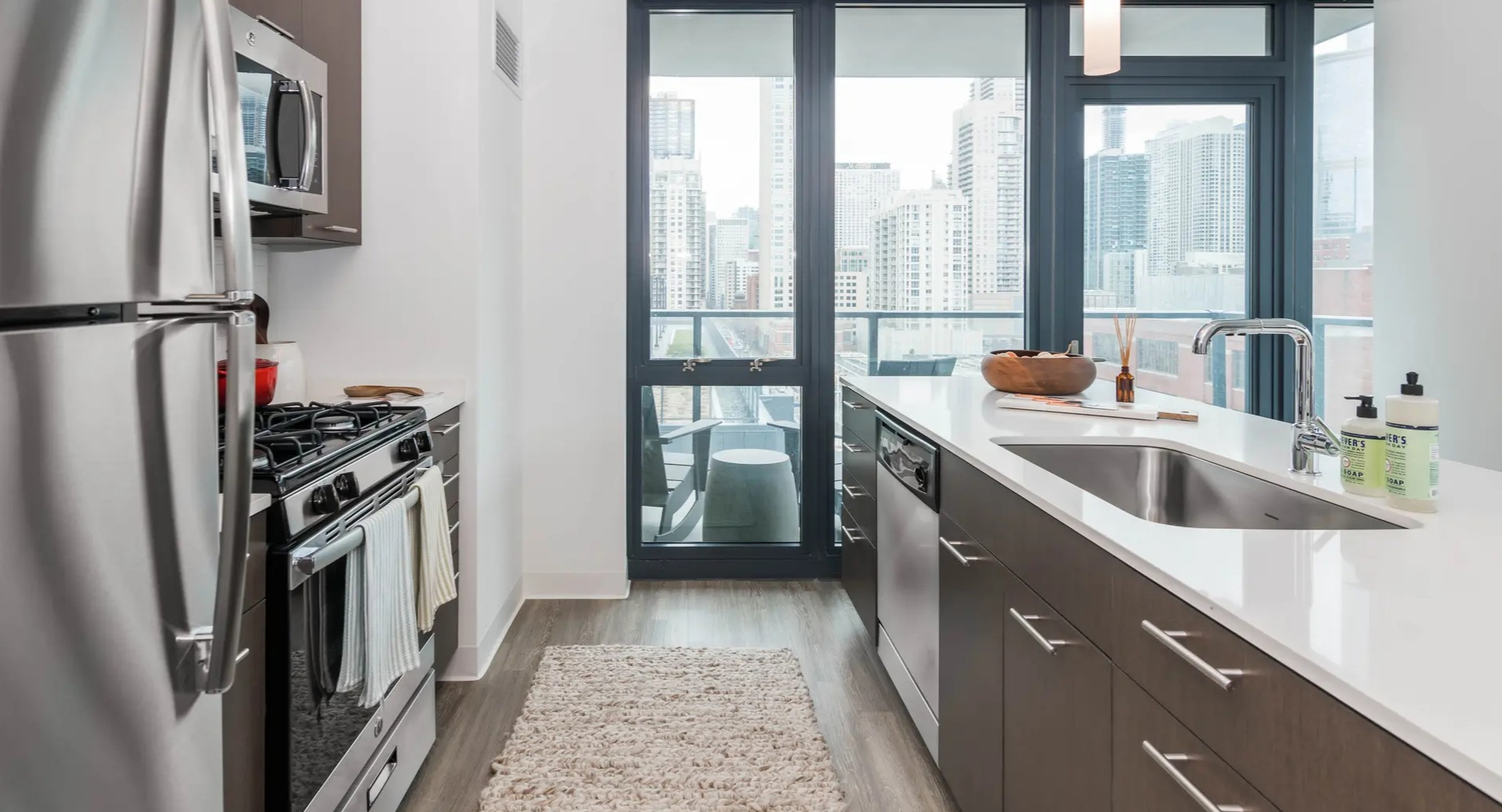 Modern galley kitchen with dark wood cabinets, stainless steel appliances, and a breakfast bar, featuring city views at The Gallery on Wells in Chicago