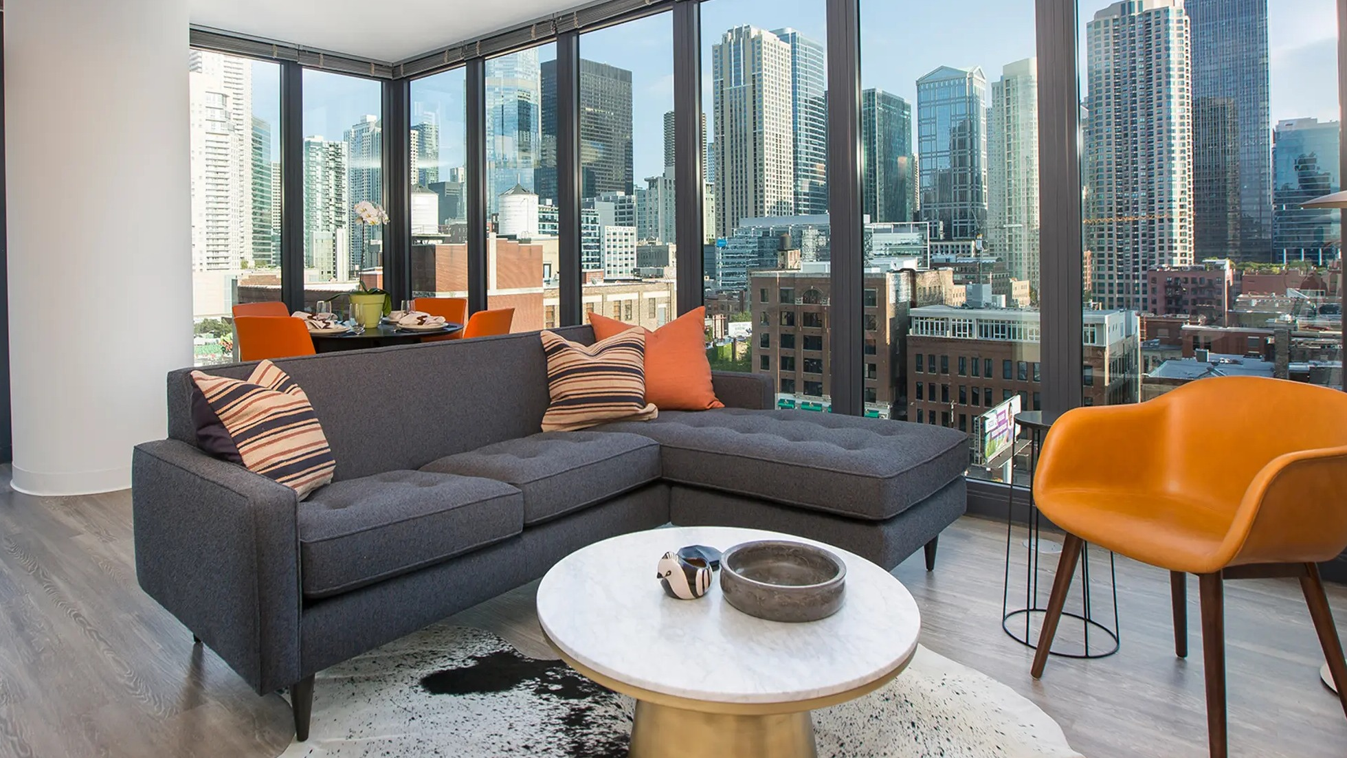 Luxurious living room with a comfortable sectional sofa, unique decor, and expansive floor-to-ceiling windows offering city views at The Gallery on Wells in Chicago