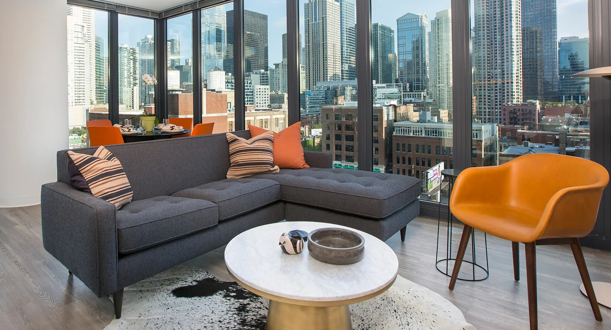 Luxurious living room with a comfortable sectional sofa, unique decor, and expansive floor-to-ceiling windows offering city views at The Gallery on Wells in Chicago