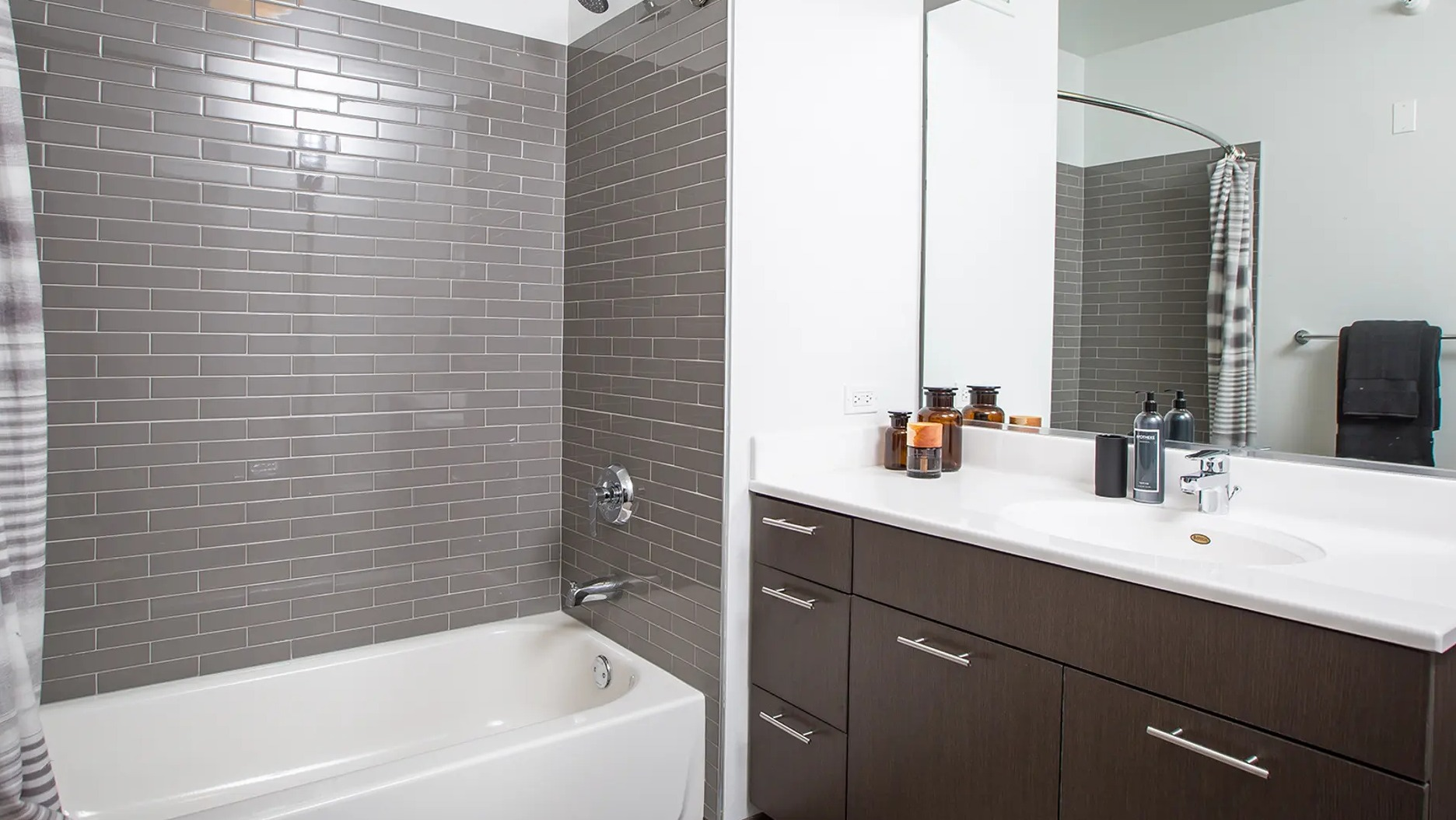 Contemporary apartment bathroom with a bathtub, subway tiled shower, and a large vanity with ample counter space at The Gallery on Wells in Chicago