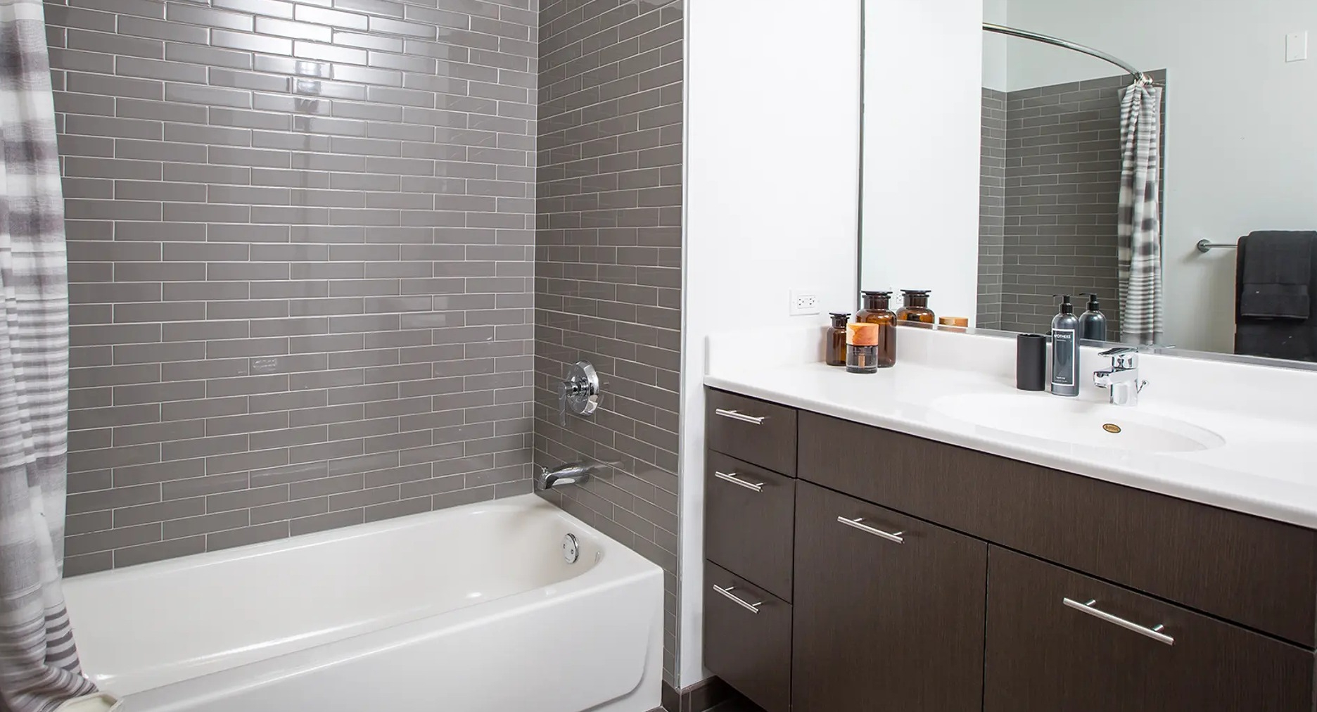 Contemporary apartment bathroom with a bathtub, subway tiled shower, and a large vanity with ample counter space at The Gallery on Wells in Chicago