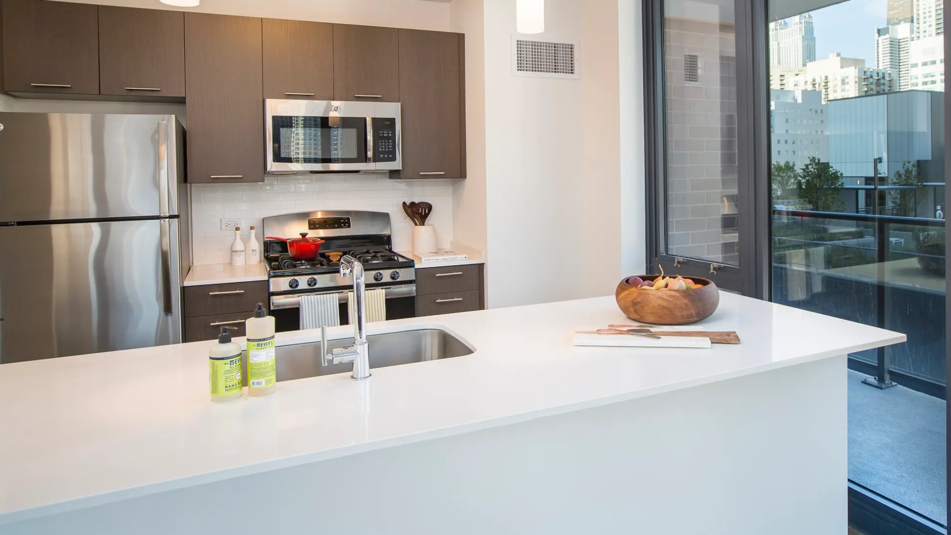 Bright open-concept kitchen and living area with city views, featuring an island, dining table, and comfortable seating at The Gallery on Wells in Chicago