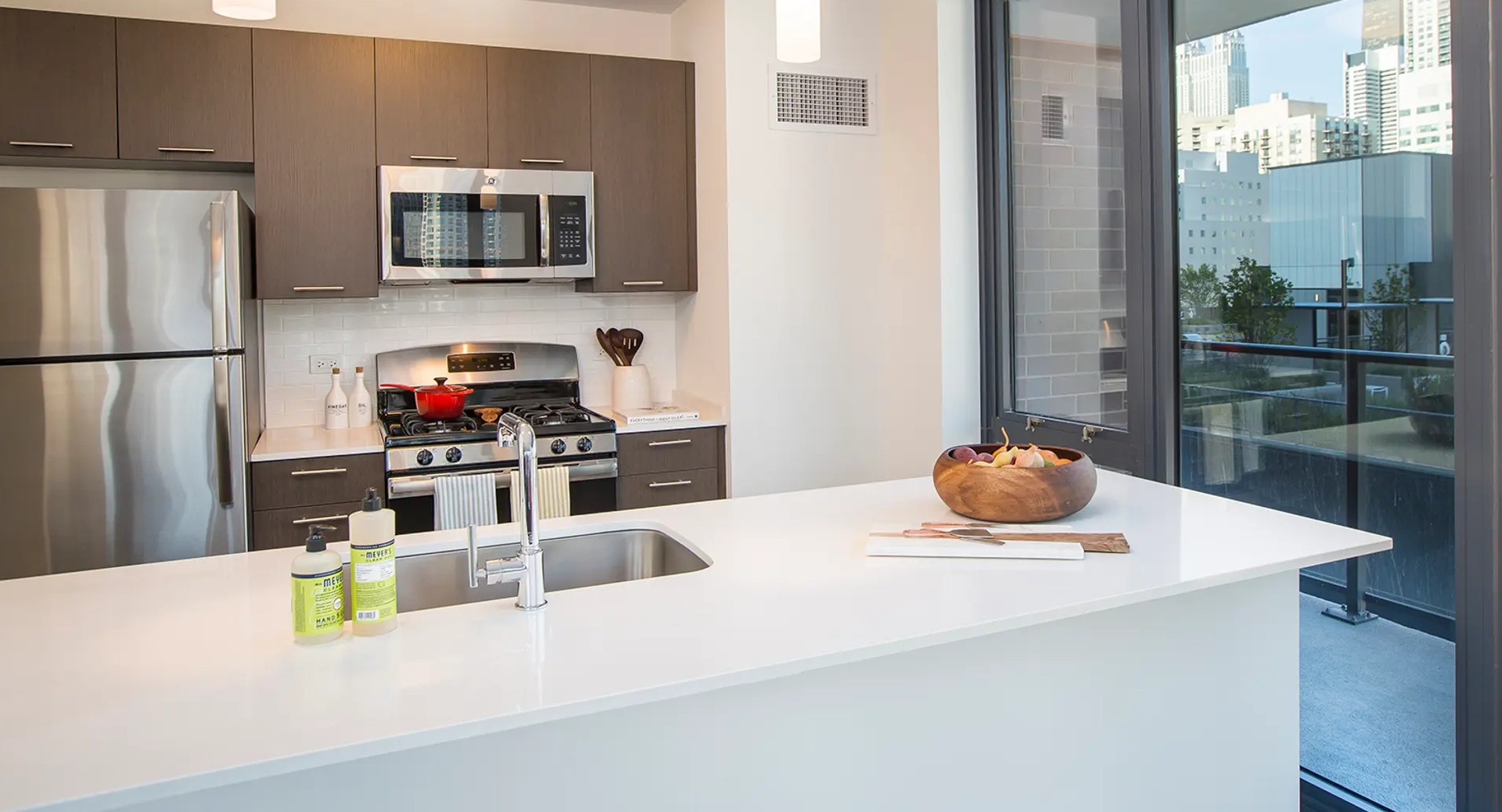 Bright open-concept kitchen and living area with city views, featuring an island, dining table, and comfortable seating at The Gallery on Wells in Chicago