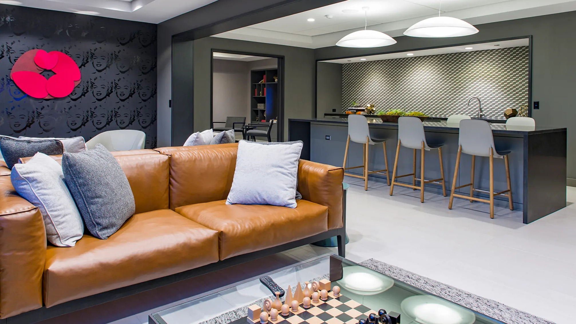 Stylish resident lounge featuring a comfortable leather sofa, chess set, and a modern open-concept kitchen with bar seating at The Gallery on Wells in Chicago