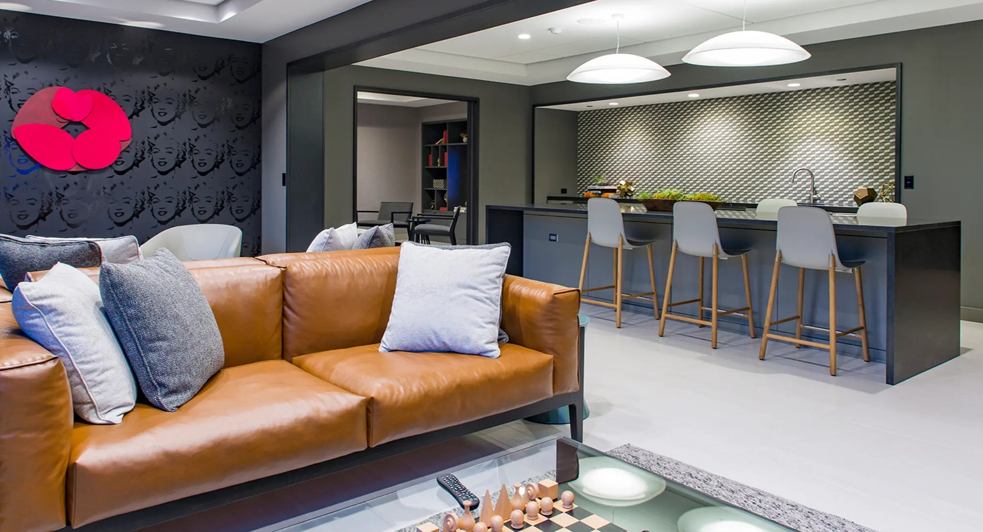 Stylish resident lounge featuring a comfortable leather sofa, chess set, and a modern open-concept kitchen with bar seating at The Gallery on Wells in Chicago