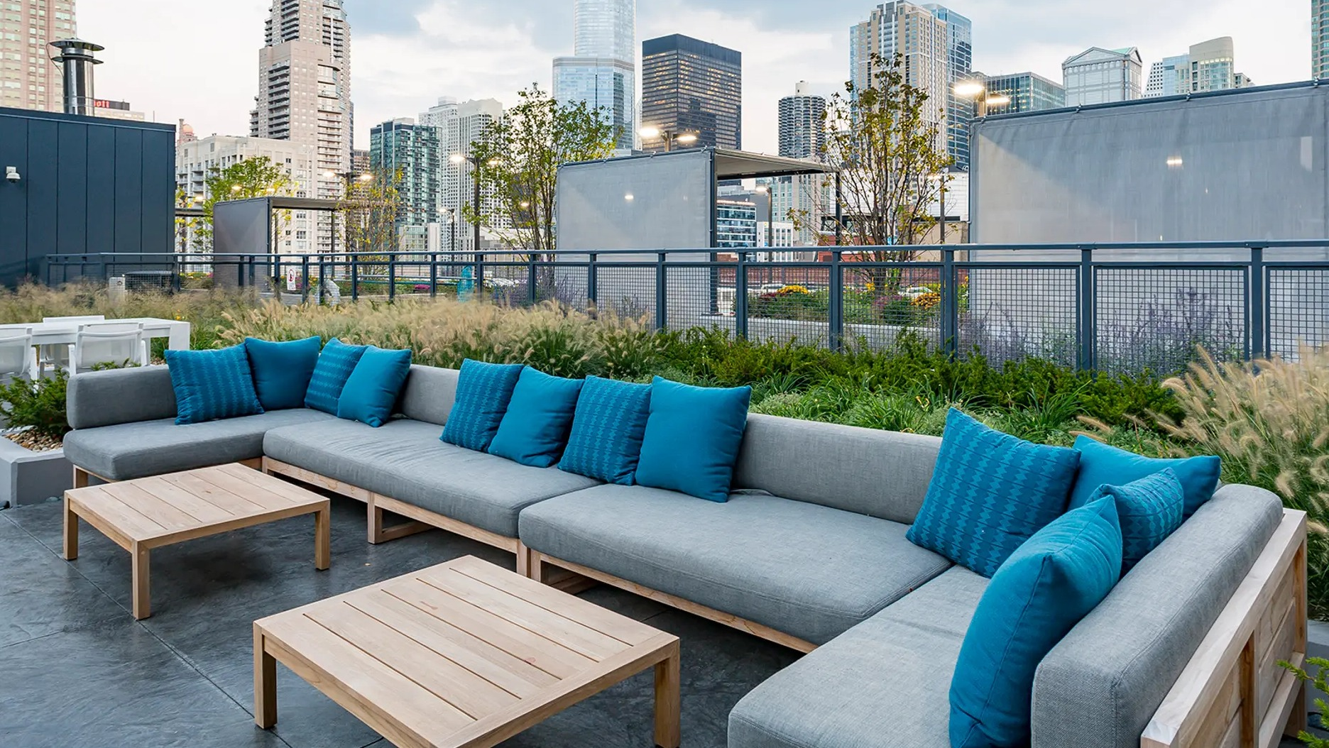 Expansive rooftop lounge with comfortable sectional sofas and stunning city skyline views, surrounded by greenery at The Gallery on Wells in Chicago