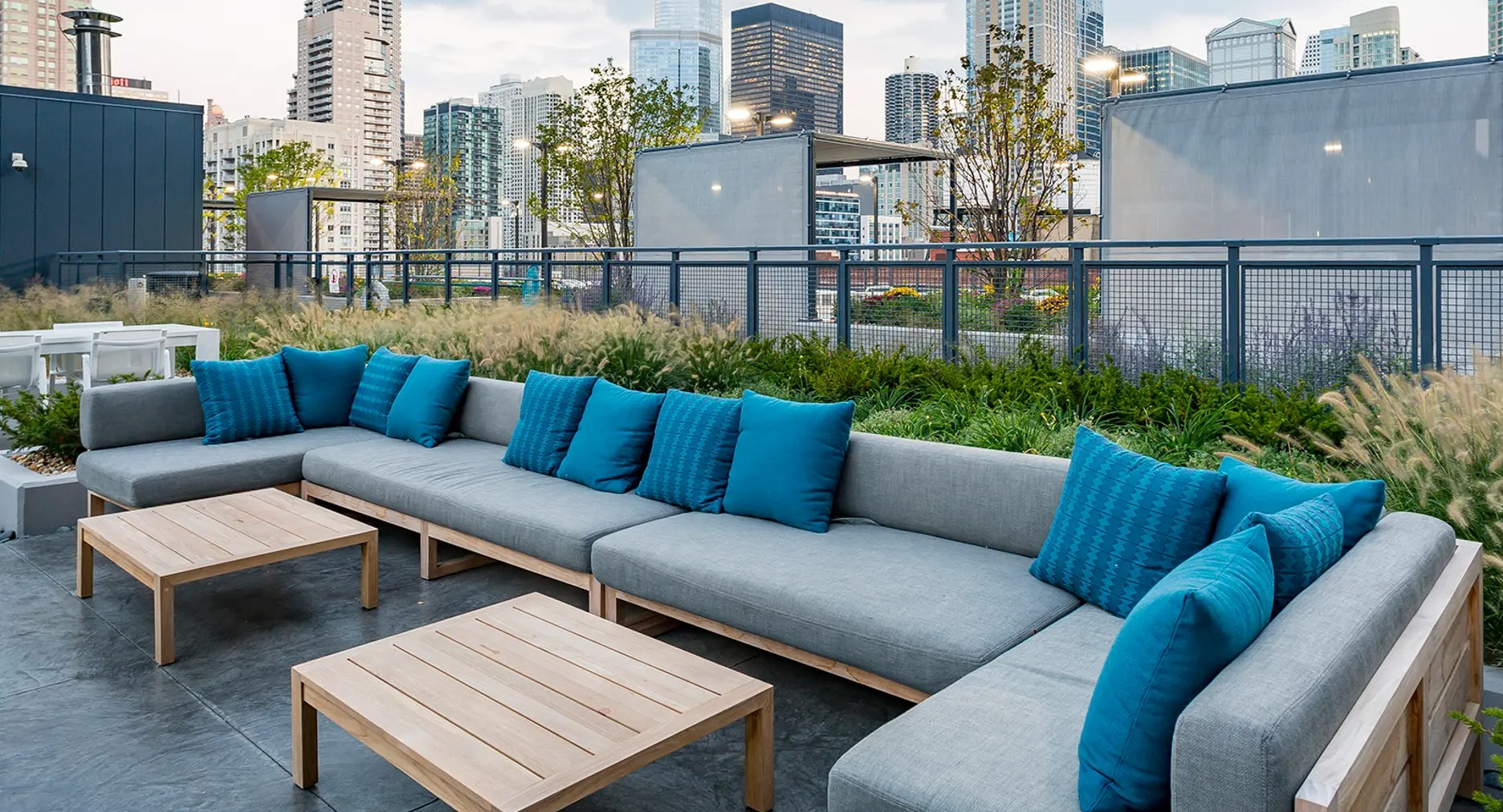 Expansive rooftop lounge with comfortable sectional sofas and stunning city skyline views, surrounded by greenery at The Gallery on Wells in Chicago