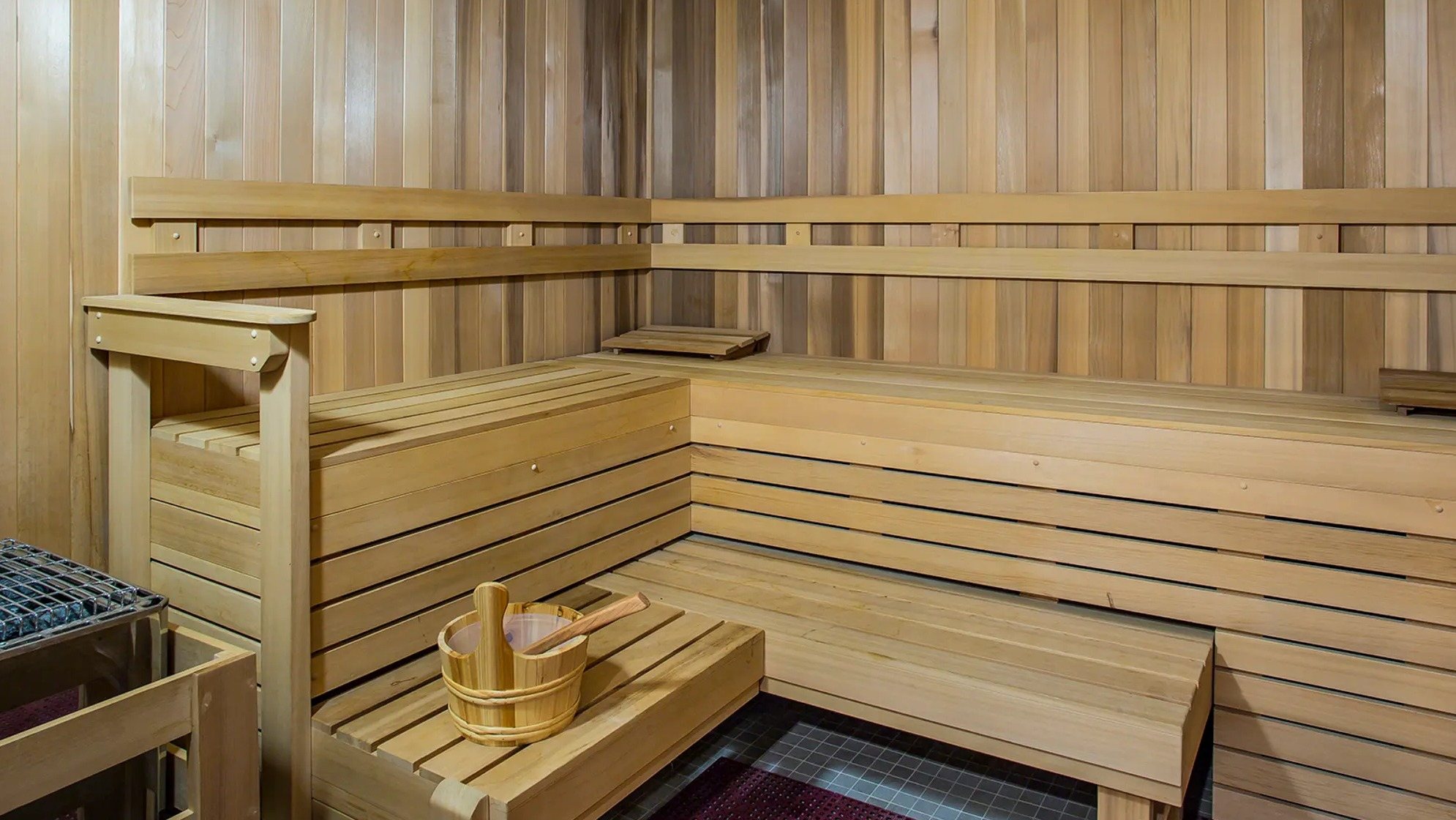 Inviting wooden sauna room with tiered benches and a traditional bucket, perfect for relaxation at The Gallery on Wells in Chicago