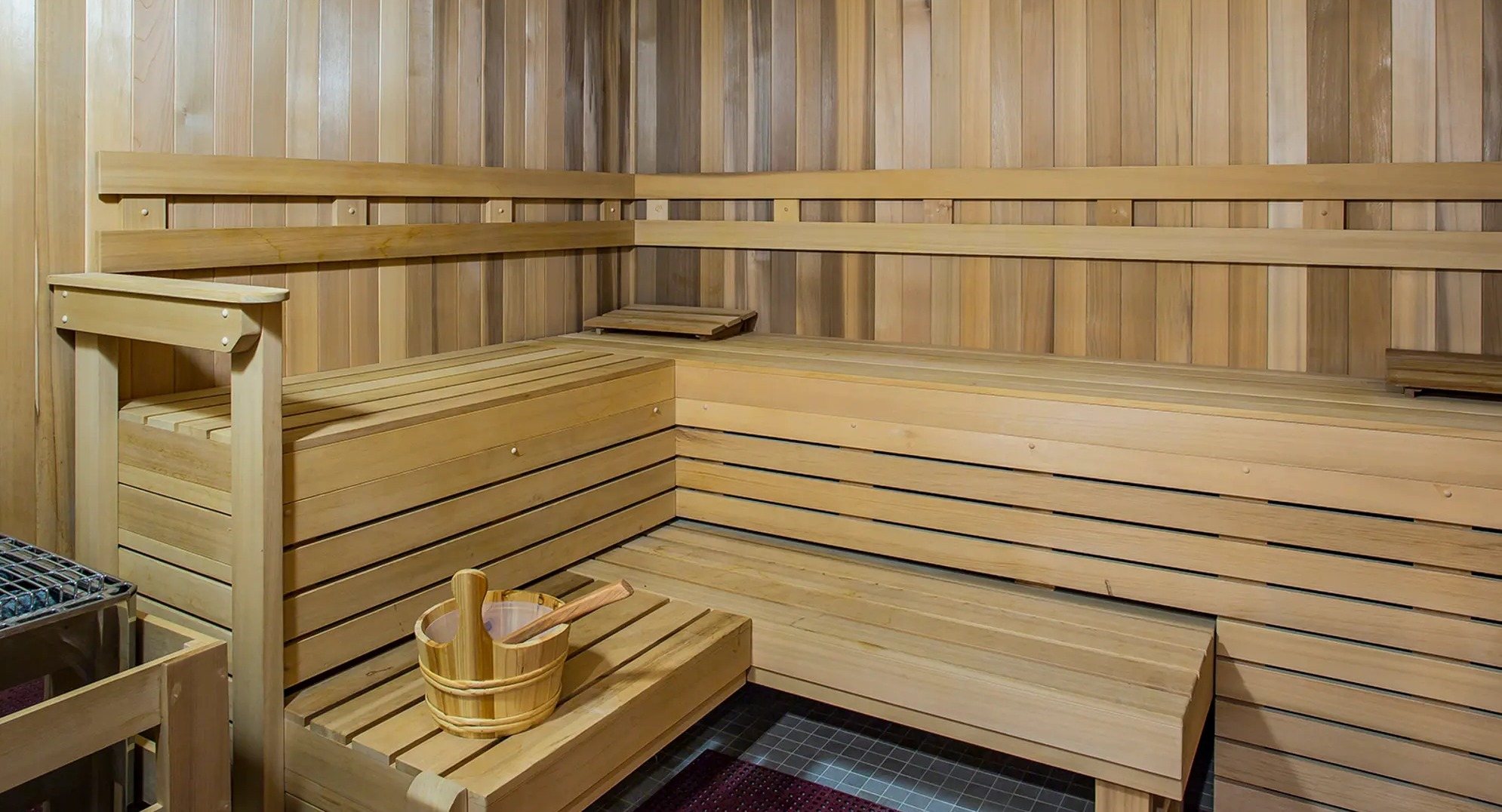 Inviting wooden sauna room with tiered benches and a traditional bucket, perfect for relaxation at The Gallery on Wells in Chicago