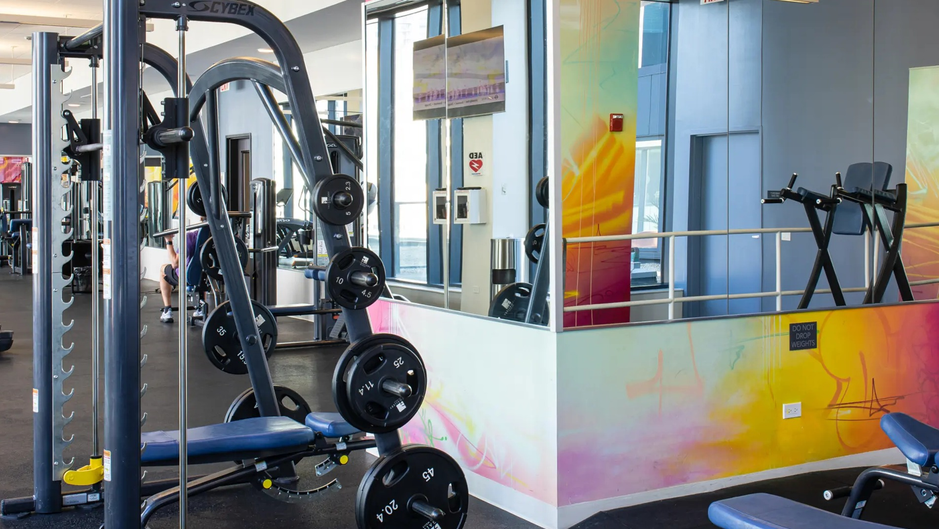 Modern strength training area with various weight machines, benches, and vibrant wall art at The Gallery on Wells in Chicago