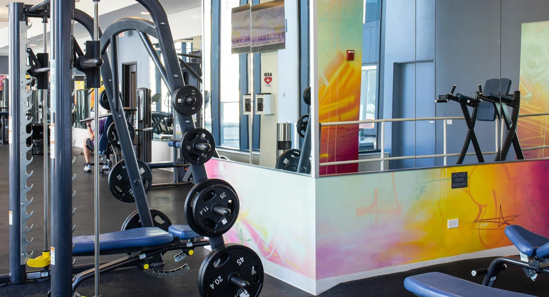 Modern strength training area with various weight machines, benches, and vibrant wall art at The Gallery on Wells in Chicago