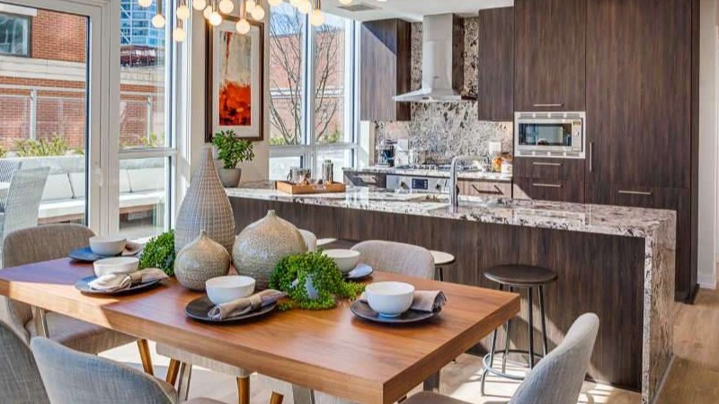 Luxurious open-plan kitchen and dining area at The Hudson in Chicago, featuring dark wood cabinetry, a large island, and city views