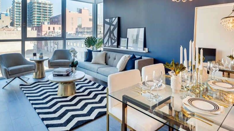 Elegant open-concept living and dining area at The Hudson in Chicago, featuring a striking chandelier and a bold blue accent wall