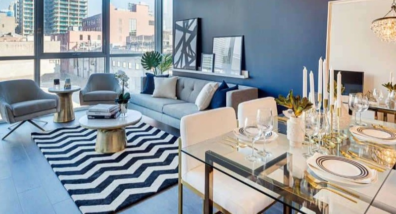 Elegant open-concept living and dining area at The Hudson in Chicago, featuring a striking chandelier and a bold blue accent wall