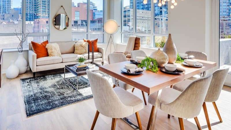Bright open-concept living and dining area at The Hudson in Chicago, featuring modern furniture, large windows, and city views.