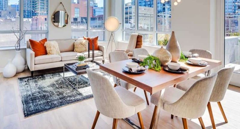 Bright open-concept living and dining area at The Hudson in Chicago, featuring modern furniture, large windows, and city views.