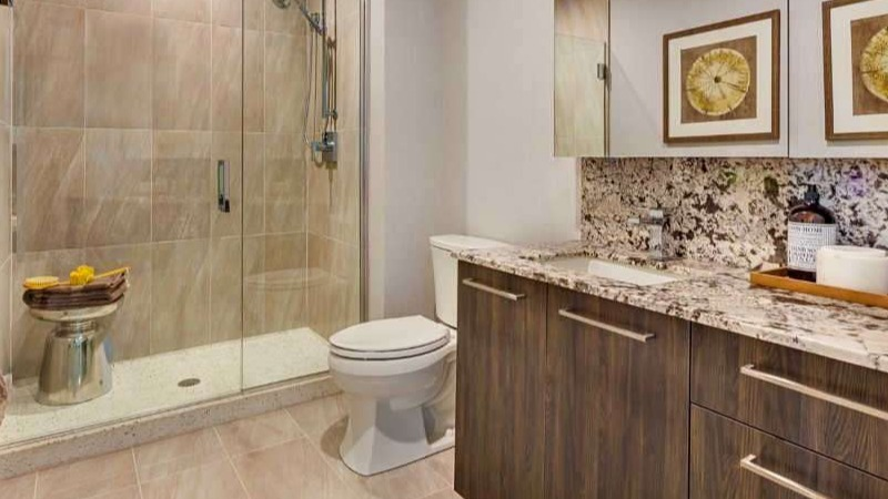 Modern apartment bathroom at The Hudson in Chicago, featuring a sleek vanity with granite, large mirror, and a spacious walk-in shower