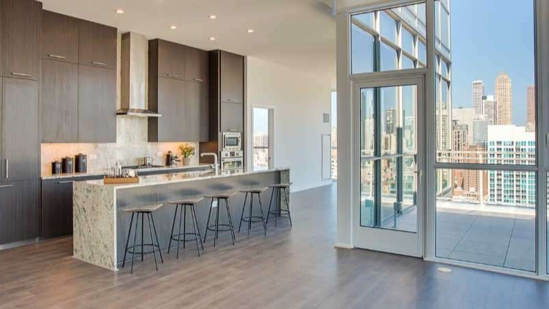 Expansive penthouse kitchen at The Hudson in Chicago, featuring dark wood cabinetry, a large island, and panoramic city views
