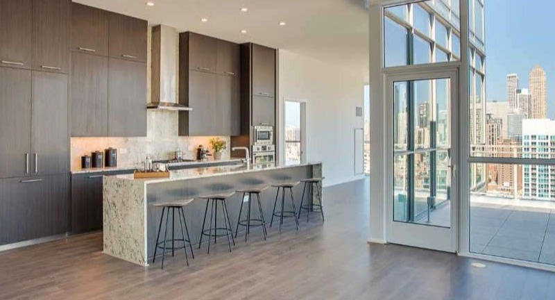 Expansive penthouse kitchen at The Hudson in Chicago, featuring dark wood cabinetry, a large island, and panoramic city views