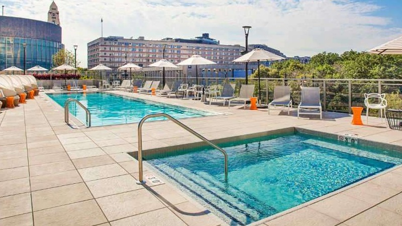 Luxurious outdoor pool and hot tub deck at The Hudson in Chicago, featuring comfortable lounge chairs and city views