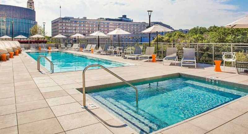 Luxurious outdoor pool and hot tub deck at The Hudson in Chicago, featuring comfortable lounge chairs and city views