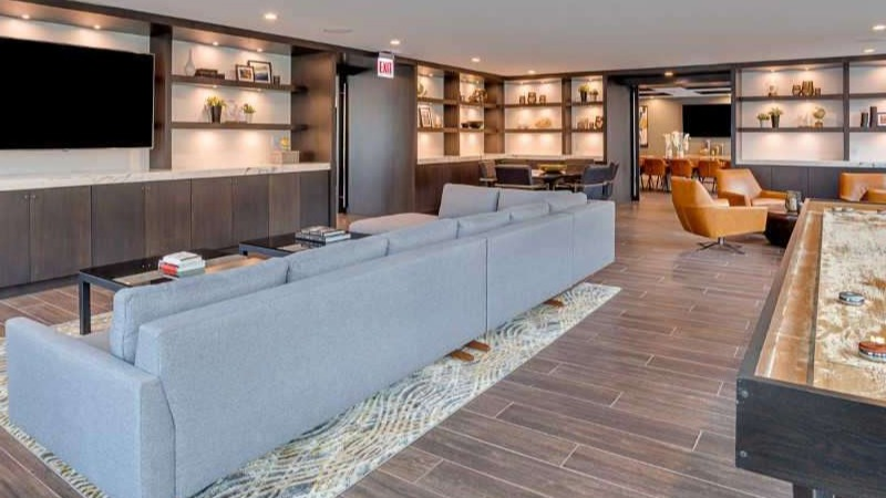 Spacious resident lounge at The Hudson in Chicago, featuring a large sectional sofa, shuffleboard, and entertainment center