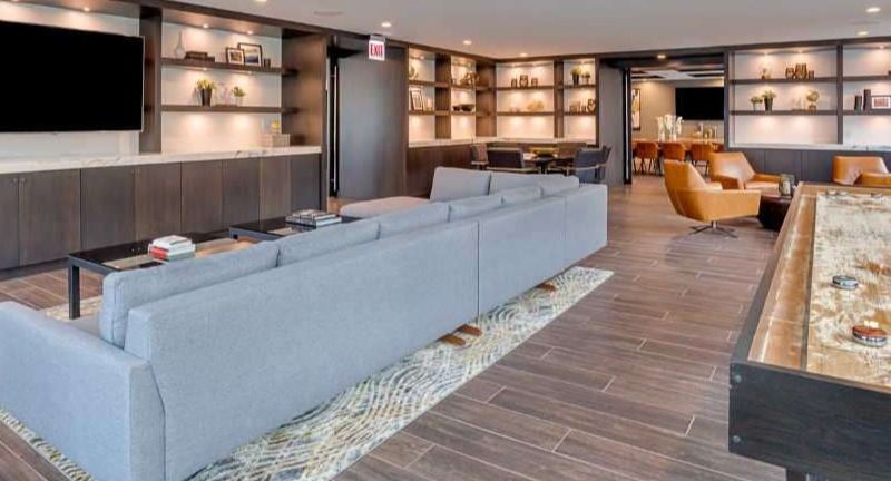 Spacious resident lounge at The Hudson in Chicago, featuring a large sectional sofa, shuffleboard, and entertainment center