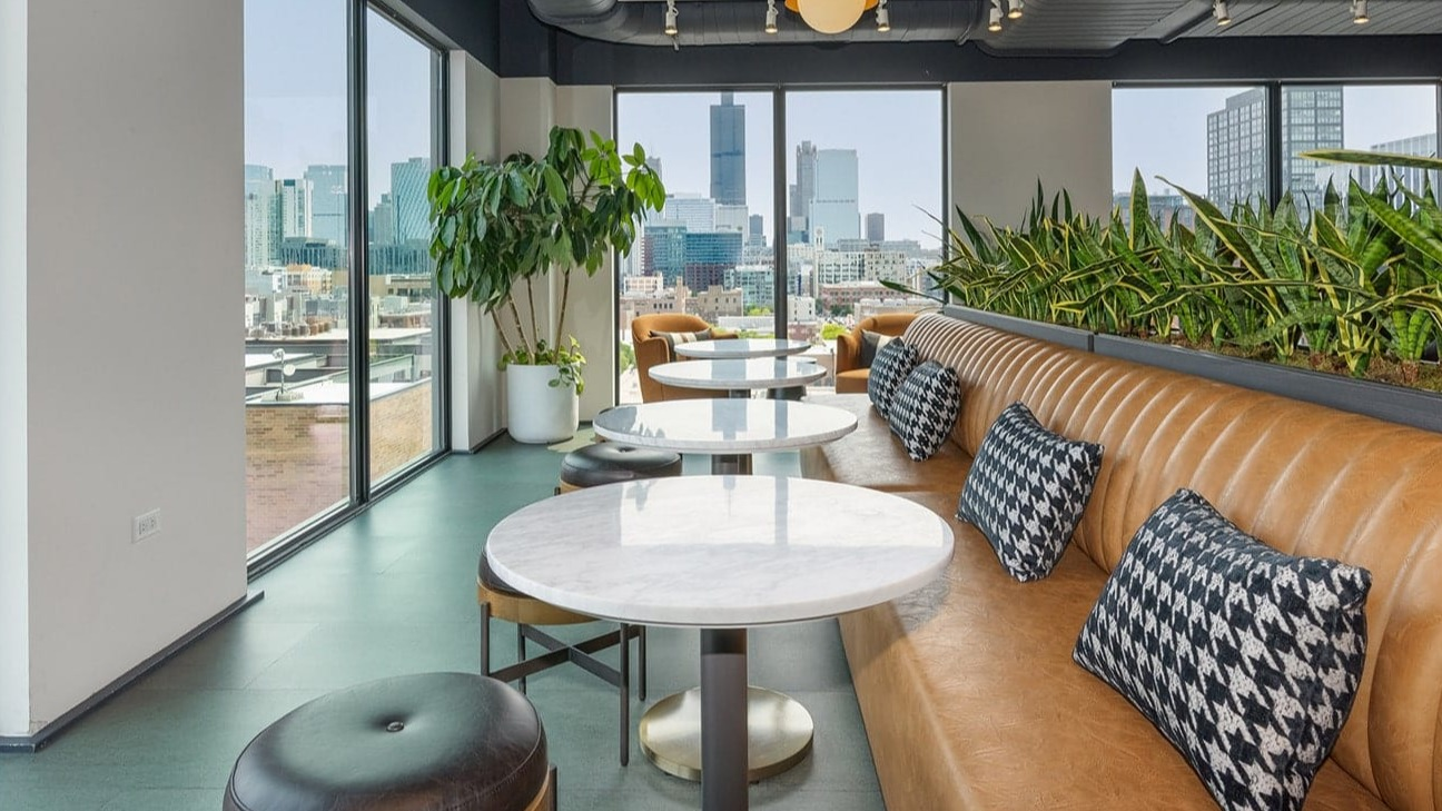 Cozy cafe lounge at The Jax in Chicago, featuring comfortable booth seating, small tables, and impressive city views
