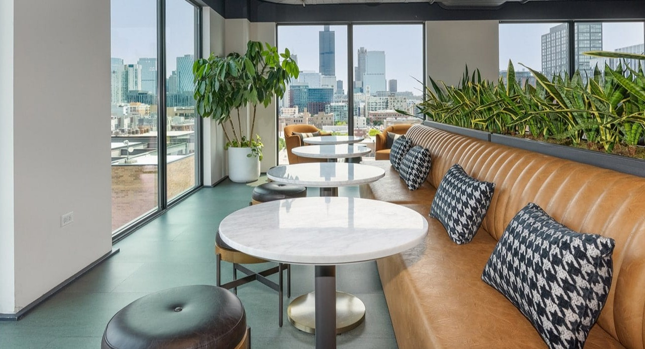 Cozy cafe lounge at The Jax in Chicago, featuring comfortable booth seating, small tables, and impressive city views