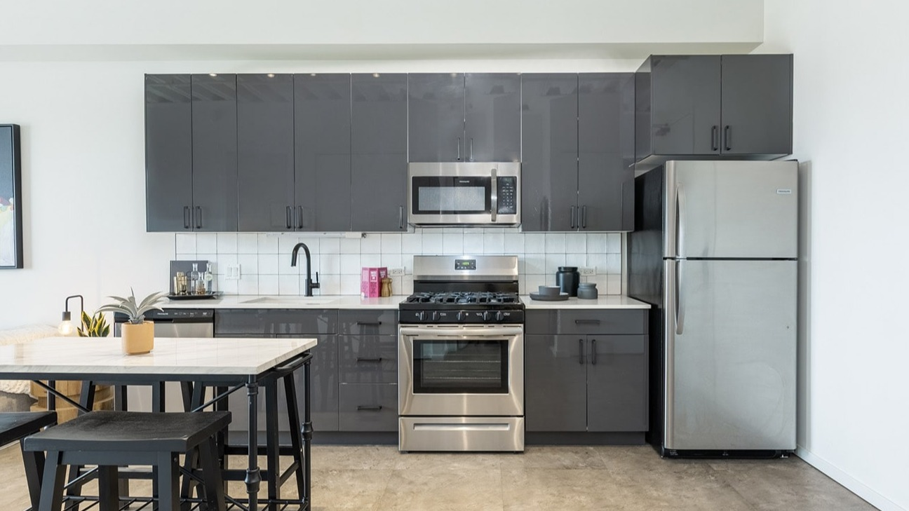 Contemporary kitchen at The Jax in Chicago, featuring high-gloss gray cabinets, stainless steel appliances, and a breakfast bar