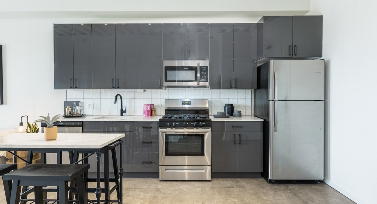 Contemporary kitchen at The Jax in Chicago, featuring high-gloss gray cabinets, stainless steel appliances, and a breakfast bar
